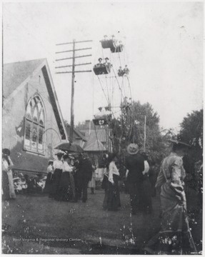 The church, built in 1897-98, was later moved in its present location on Temple Street and Fifth Avenue in 1907. A ferris wheel sits outside of the building while unidentified subjects gather on the lawn. 