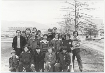 Hylton, pictured far right with a cigar in his mouth, stands with a group of kids from Hinton, W. Va. The WVU stadium is pictured in the background.