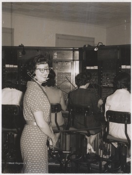 An unidentified woman watches employees at the Chesapeake & Potomac Telephone Exchange. 