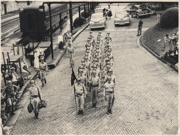 A group of unidentified soldiers march down the brick road. 