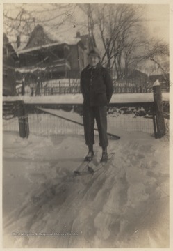 The unidentified boy poses on the snowy ground while wearing skis.