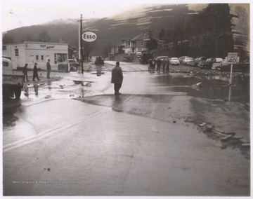 Groups of people stand by the street to observe the flooding.