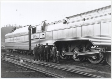 A group of unidentified men and small boy stand beside the massive C. & O. engine. 