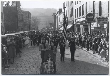 A crowd watches from the sidewalk as Boys Scouts, military men, and a marching band move through Temple Street.