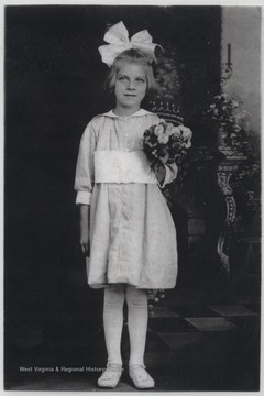 Plumley pictured in a nice dress and bow holding a bouquet of flowers. She married John H. Plumley, a sheet metal worker for the C. & O. Railroad, in 1928. In 1930, she began to work for the railway, as well, and in 1948 became the Chief Operator. She has one son, John Jr. Plumley.