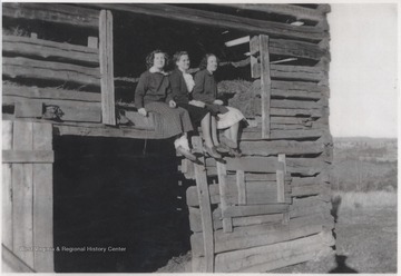 Gladys, Lillian, and Glenna Shumate sit outside a barn window.