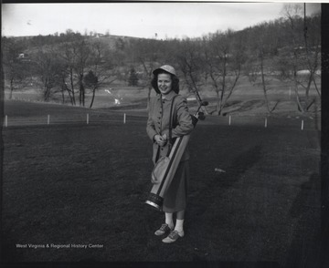 An unidentified woman is pictured with golf gear on the green. 