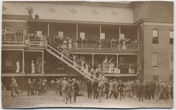 People are crowded along the balconies and staircase of the building. The atmosphere of the photo suggests an excitement in the air, perhaps in anticipation of a parade.