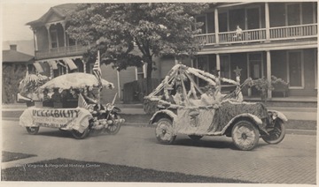 The two decorated vehicles make their way down Temple Street. The float in back advertises Plumley-Hulme Co. 