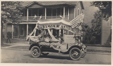 Three unidentified children sit inside the vehicle decorated with streamers and American flags on Temple Street. 