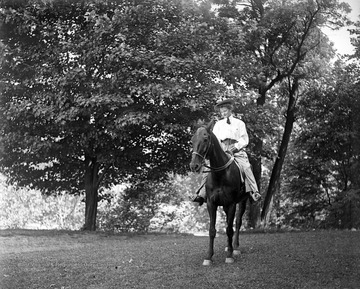 File was labeled "person on horse."  This is an image of Leila Jesse Frazier, one of the first women to graduate from the WVU School of Law in 1899. At the beginning of her time at the school of Law, she arrived in Morgantown unaccompanied from Martinsburg, W. Va. riding a horse in "man fashion."