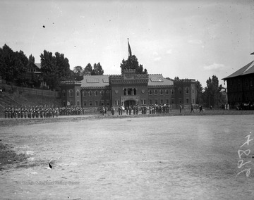 Image shows a cadet drill in front of the WVU Armory from the Agricultural Experiment Station.