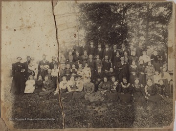Professor Keadle, the middle age, older gentleman standing in the center of the photo, poses with family members and attendees of an exercise on the New River. Keadle was a locally noted school teacher int he New River Valley during the turn of the century.On the right hand side of the photo is the corner of the school building.