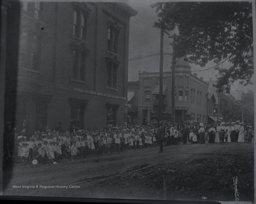 Spectators line the sidewalks beside the First National Bank of Hinton and National Bank of Summers awaiting the parade procession.  Subjects unidentified.