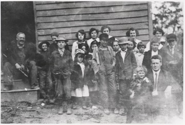 Teacher at the bottom right is George C. Cottle. Cottle's grandfather, Bob Wood, is sitting in the doorway. The children are unidentified. 