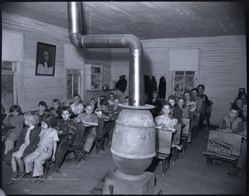 The unidentified school children are pictured behind their desks. A heater sits in the middle of the classroom. 