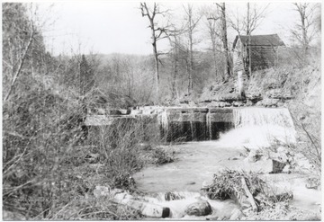 The mill is pictured among the trees on the right overlooking the waterfall.
