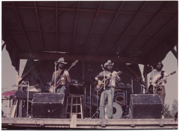 Pictured on stage is a pianist, bassist, two guitarists, and a drummer. Subjects unidentified. This photograph is from a collection taken at Appalachian Folk Music Festivals, including the Ivydale and John Henry festivals. 