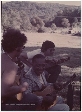 This photograph is from a collection taken at Appalachian Folk Music Festivals, including the Ivydale and John Henry festivals. Here three men are pictured playing the guitar. Subjects unidentified. 