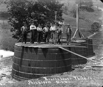 Unidentified men stand on oil tanks