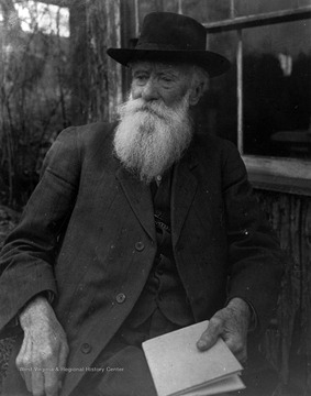 Burrows is pictured holding a book and sitting by a cabin likely in West Virginia.