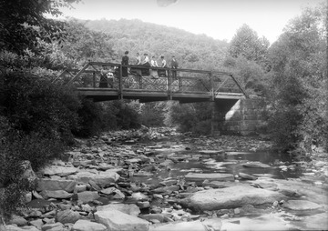 "Iron Bridge Up M & K Railroad."  Men and women stand on a bridge over a creek.