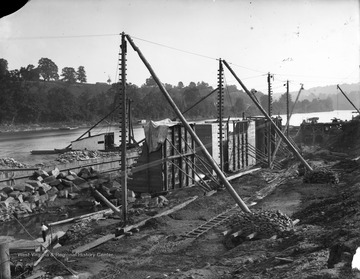 View of construction site of a lock and dam with crew members along Monongahela River.