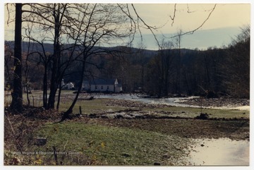 A church in Onego, W. Va. is surrounded by water from a creek that used to be behind it.  The flooded and muddy field was previously a green pasture. The damage occurred during the November 1985 flood in the area around Parsons, Elkins, Onego, and Mounth of Seneca, W. Va.