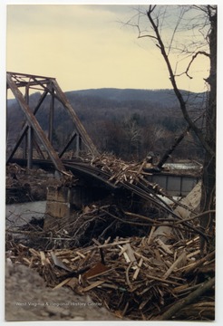 Debris surrounds the damaged bridge and railroad tracks.  The damage occurred during the November 1985 flood in the area around Parsons, Elkins, Onego, and Mounth of Seneca, W. Va.