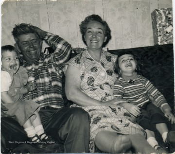 Cousins Donna and Judy Ann Sirk, sitting on the sofa with grandparents, James and Pauline Sirk.