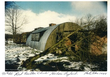 A snowy scene of the 95th BG [Bomb Group] "Red Feather Club" shows a tree fallen over near one building. 