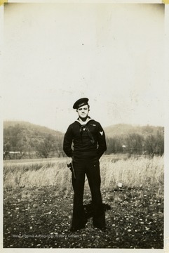 Marshall L. Williamson, U.S. Navy Medical Corps, assigned to the 57th Naval Construction Battalion (Seabees), stands in his naval uniform in a field at his home in West Virginia.