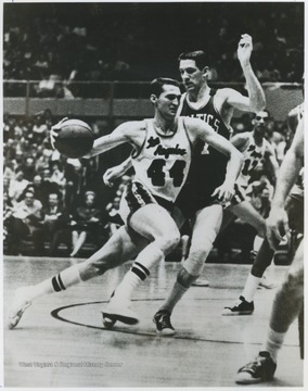 West (No.44), a twelve-time all-star by the time of this photograph, accelerates past Celtics player John Havlicek. 