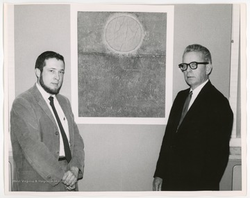 West Virginia artist Bernie Peace taught at West Liberty State College in the Wheeling area for 35 years, from 1960-1995.  In this image, Bernie Peace and William Martin stand next to a work of art.