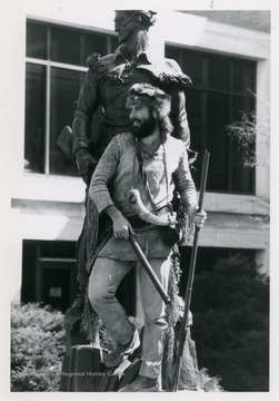 West Virginia University's 1986-1987 mascot poses with Mountaineer Statue located outside of the Mountainlair on the downtown campus.