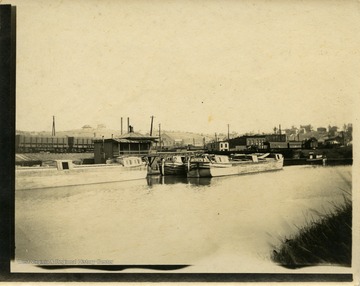 This image is part of the Thompson Family of Canaan Valley Collection. The Thompson family played a large role in the timber industry of Tucker County during the 1800s, and later prospered in the region as farmers, business owners, and prominent members of the Canaan Valley community.The image shows canal boats and a train in the background.