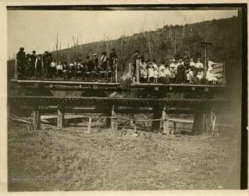 This image is part of the Thompson Family of Canaan Valley Collection. The Thompson family played a large role in the timber industry of Tucker County during the 1800s, and later prospered in the region as farmers, business owners, and prominent members of the Canaan Valley community.Large group of unidentified people, men in left car and women in the right car, pose in train cars while taking the railroad to Blackwater Falls for a picnic.