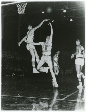 West jumps to block GW's George Marshall and his layup shot during this 1958 game.  WVU won 93 to 66.