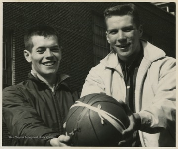 Stover and Green pose with the game ball after securing the state championship victory.Jerry West led the East Bank High School basketball team to its first ever West Virginia state championship title. He was named All-State from 1953–56, then All-American in 1956 when he was West Virginia Player of the Year, becoming the state's first high-school player to score more than 900 points in a season.West was born in Cheylan, W. Va. in 1938. After high school, he went on to play basketball for West Virginia University and then rose to fame as a player for the Los Angeles Lakers of the NBA before becoming a basketball coach and manager. 