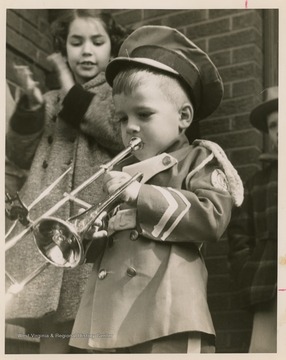 Clinton Jeffreys, mascot for the East Bank High School band, blows a horn to celebrate the homecoming of the State Basktball Champion, East Bank High School, as Susie Williams, age 8, cheers behind him.