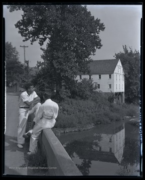 Two unidentified boys look out over the water beside the historic building. 