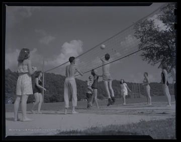 Unidentified teens play a game of volleyball in an unidentified location. 