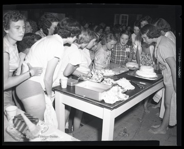 A group of unidentified girls inspect the desserts left on the table. 