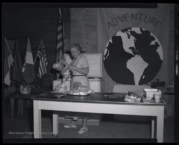 An unidentified woman pulls bags of frozen food from a nearby freezer in preparation for the demonstration to young, female campers.