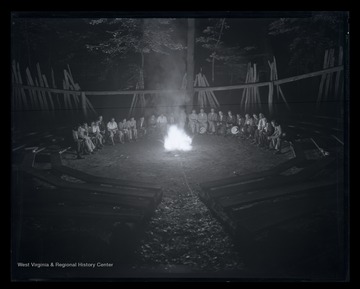 A group of camp counselors gather around the campfire. Subjects unidentified. 