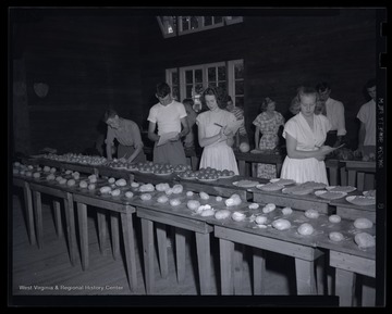 A group of men and women examine vegetables laid out on tables. Subjects unidentified. 