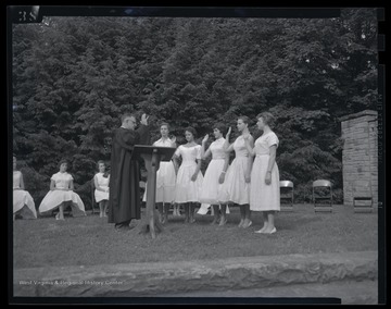 A group of girls take an oath in front of their peers. Subjects unidentified. 