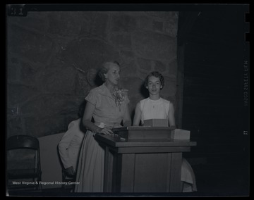 Mrs. Reynolds, left, stands at a podium with the 'governor' of R. Girls State, who is unidentified. 