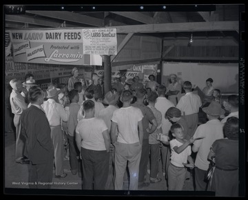 A group is gathered around the Larro Dairy Feeds exhibit. 