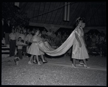 Young girls carry the cape train as the health King and Queen proceed through the room. 